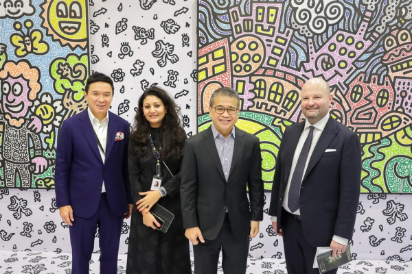 Four formally dressed people stand in front of a colourful mural at Singapore's Art SG art fair.