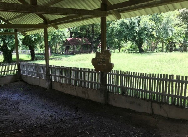 An open air room looks over a patch of grass marking the Choeung Elk killing field in Cambodia. 